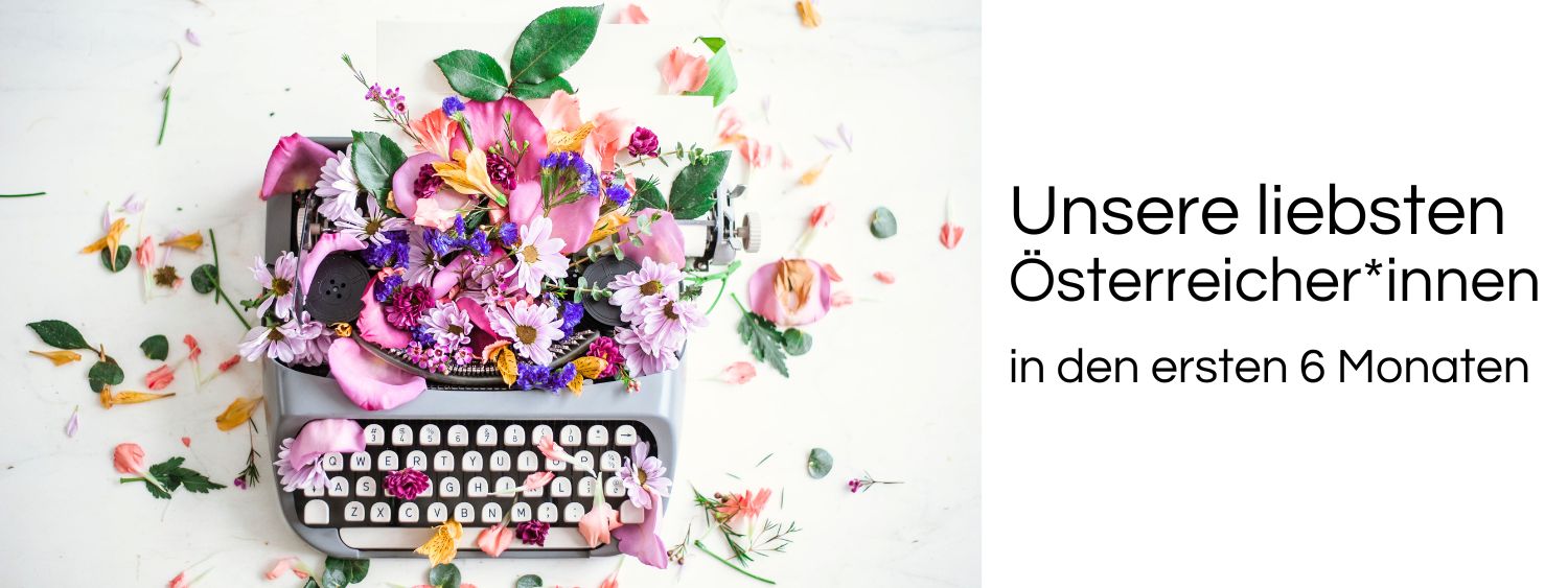 Schreibmaschine mit Blumen. Link zu unserem Onlineschaufenster Unsere liebsten Österreicher*innen.